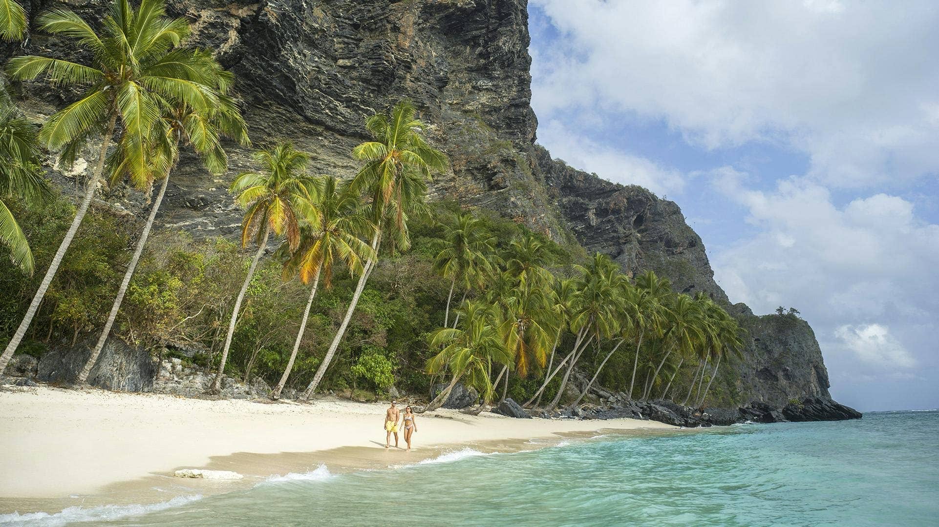 Playa escondida Samaná Las Galeras – pareja caminando en playa virgen con palmeras y acantilados